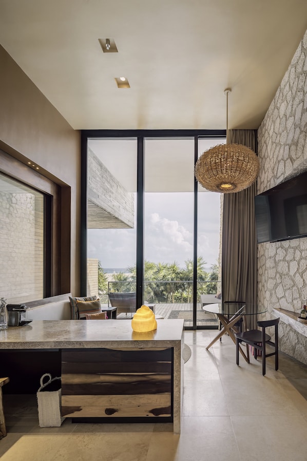 Una cocina moderna con una isla grande, comedor y una pared decorativa de piedra.
