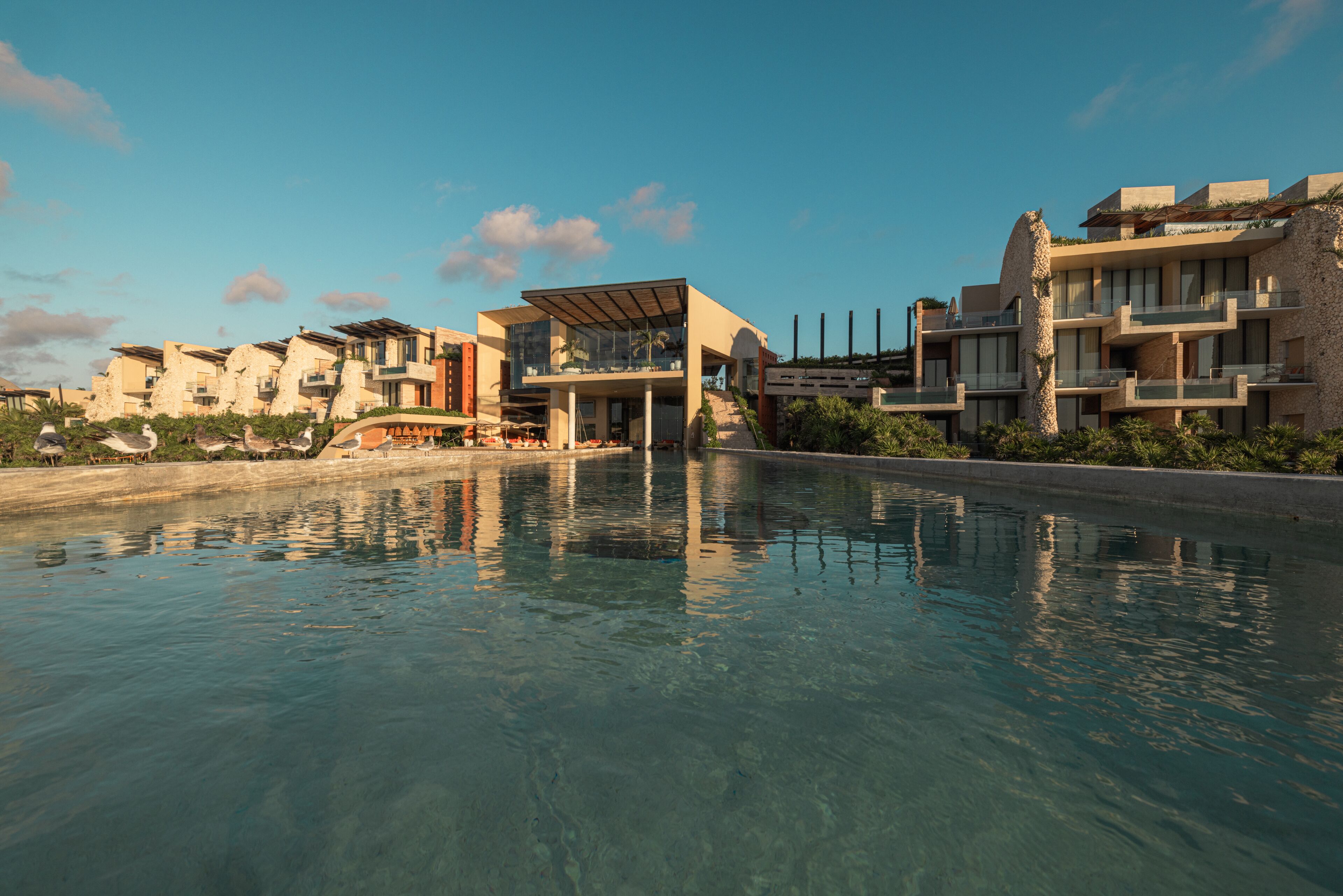 Un resort moderno con piscina, edificios de varios pisos y un cielo despejado.