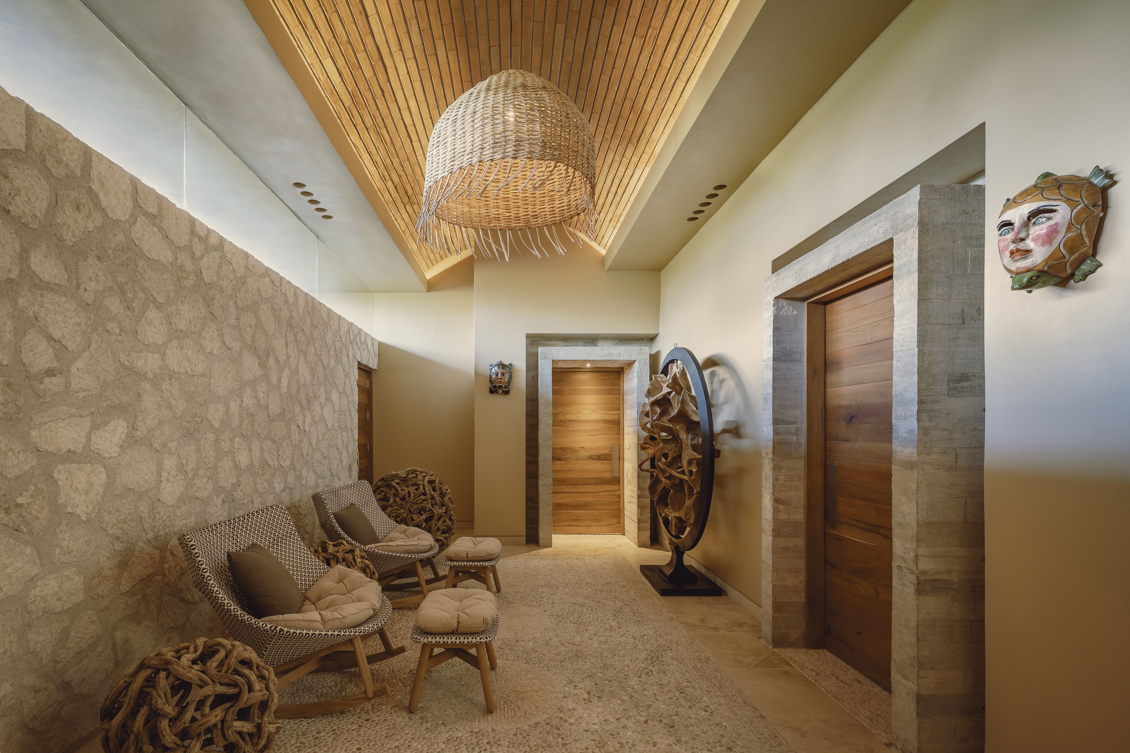 A hallway with stone walls, wicker furniture, and a wooden ceiling.