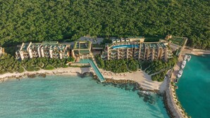 An aerial view of a resort with multiple buildings, a beach, and a pier extending into turquoise waters. - La Casa de la Playa by Xcaret-All Inclusive, Adults Only (Playa del Carmen)