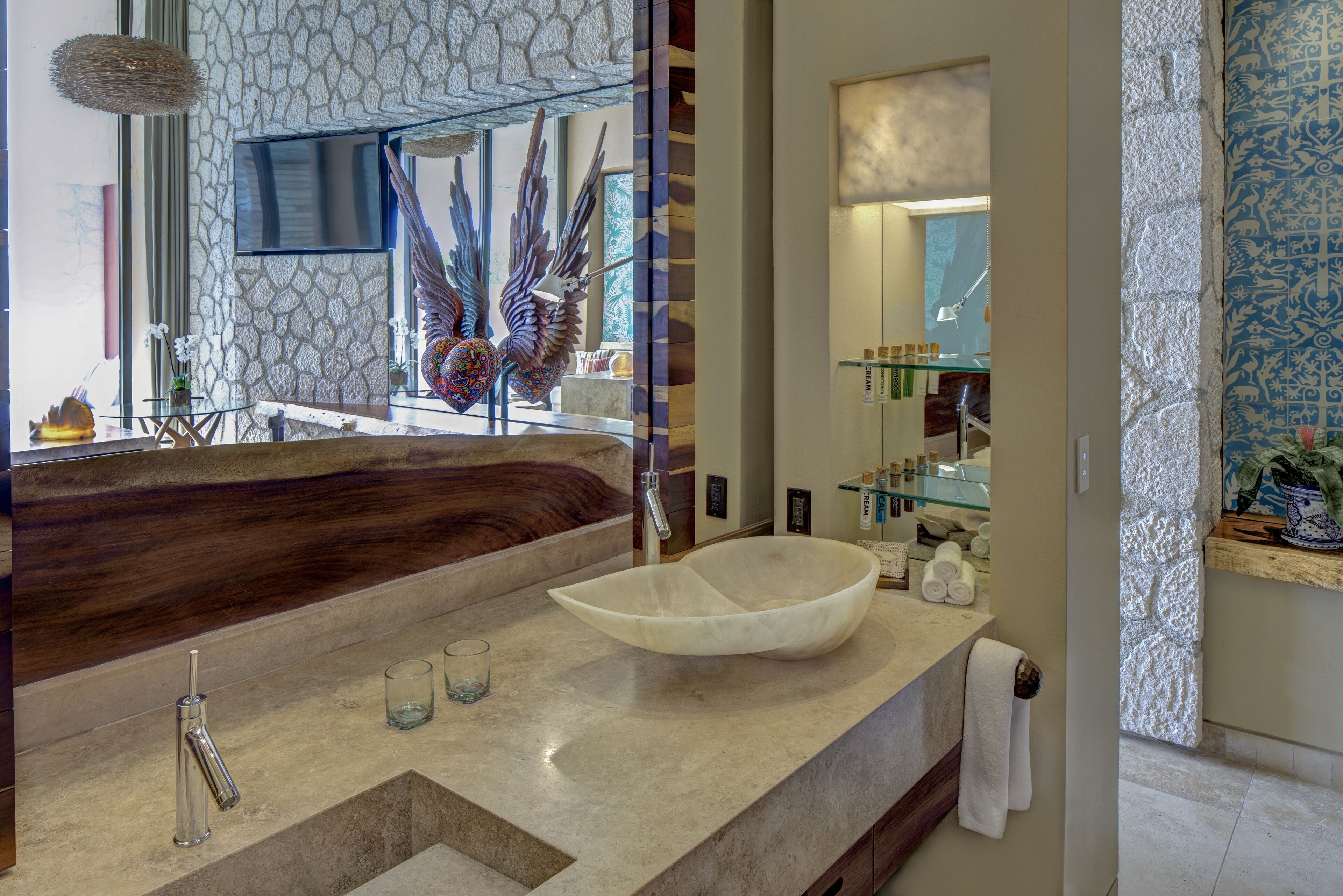Un baño moderno con un espejo grande, una escultura única de un pájaro y un lavamanos blanco de gran tamaño.