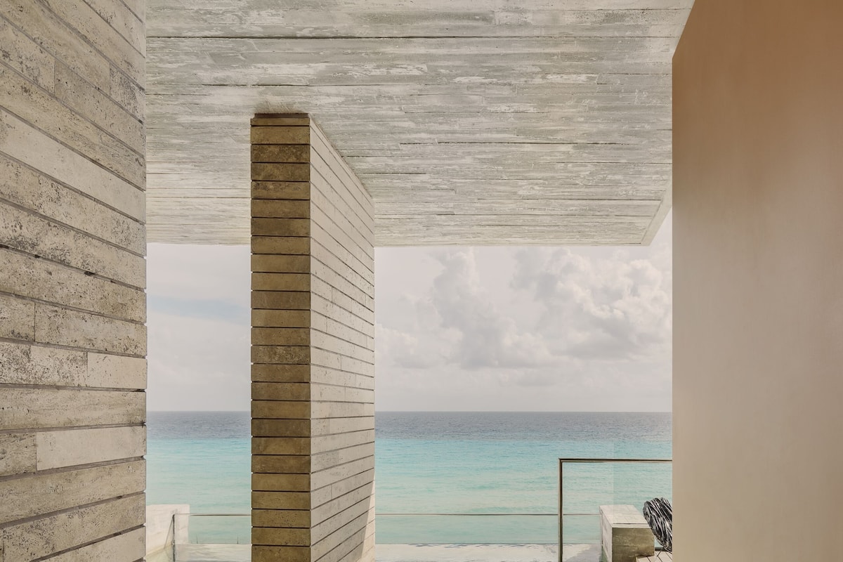 A modern spa room with a large bathtub, a view of the ocean, and a wooden ceiling.