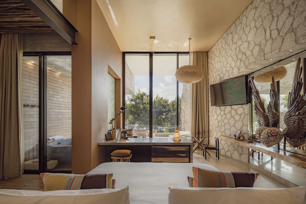 A modern hotel room with a large bed, a desk, and a TV.