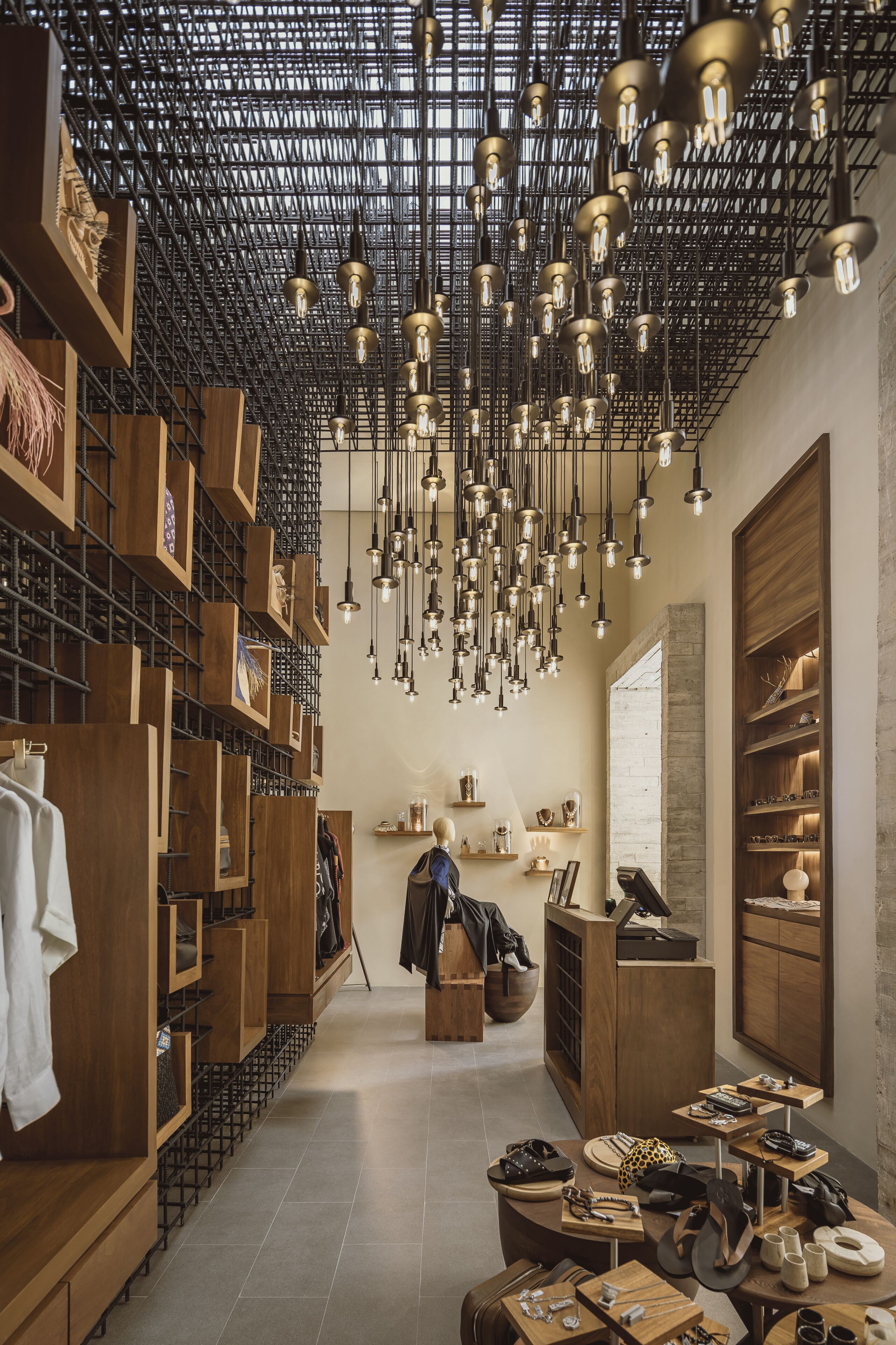 A boutique hotel interior with wooden shelving, a central seating area, and hanging light fixtures.