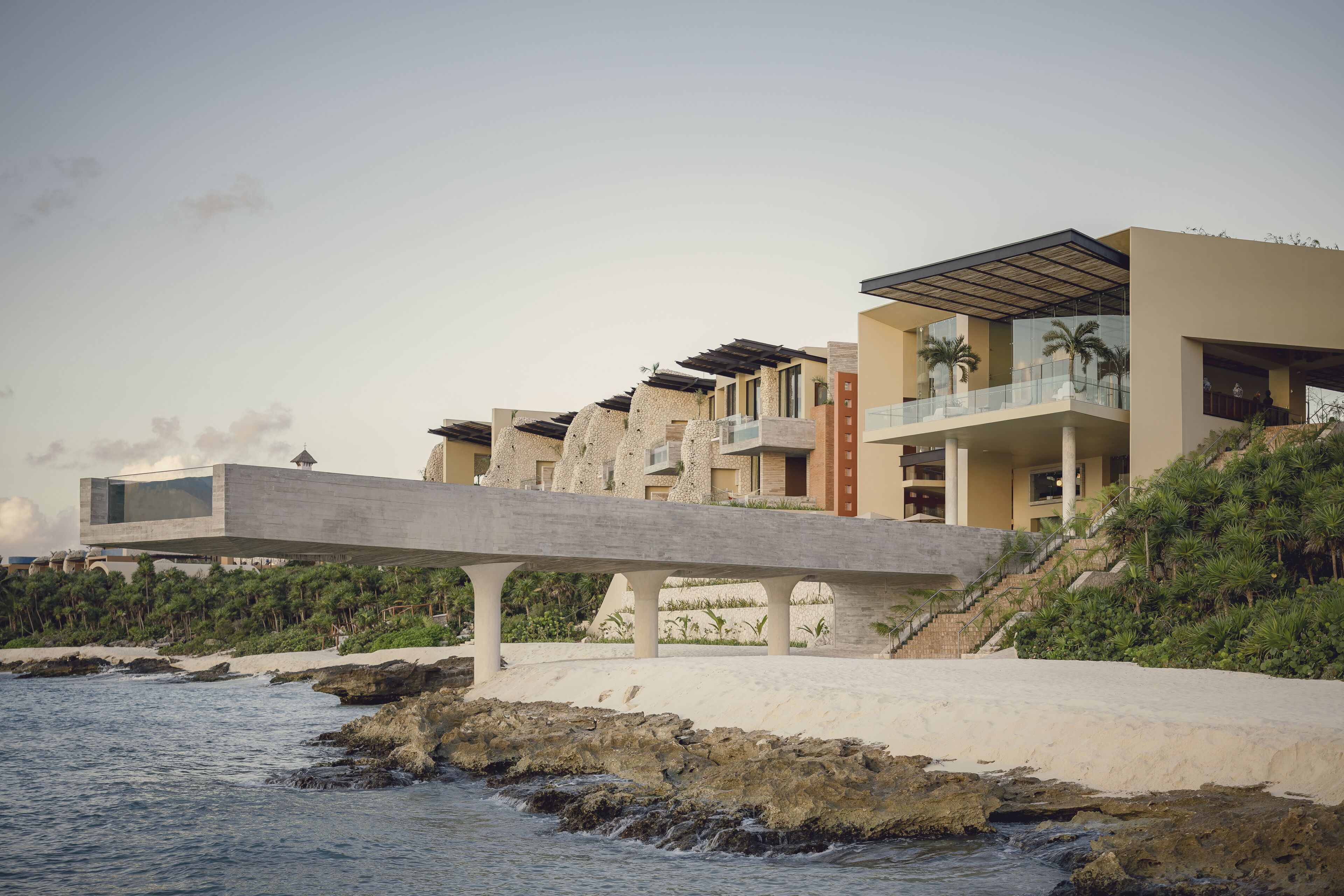 Un hotel costero con diseño arquitectónico moderno, que cuenta con varios balcones y una estructura destacada sobre el agua.