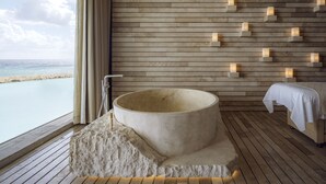 A spa room with a large stone bathtub, wooden slats on the wall, and a view of the sea. - La Casa de la Playa by Xcaret-All Inclusive, Adults Only (Playa del Carmen)