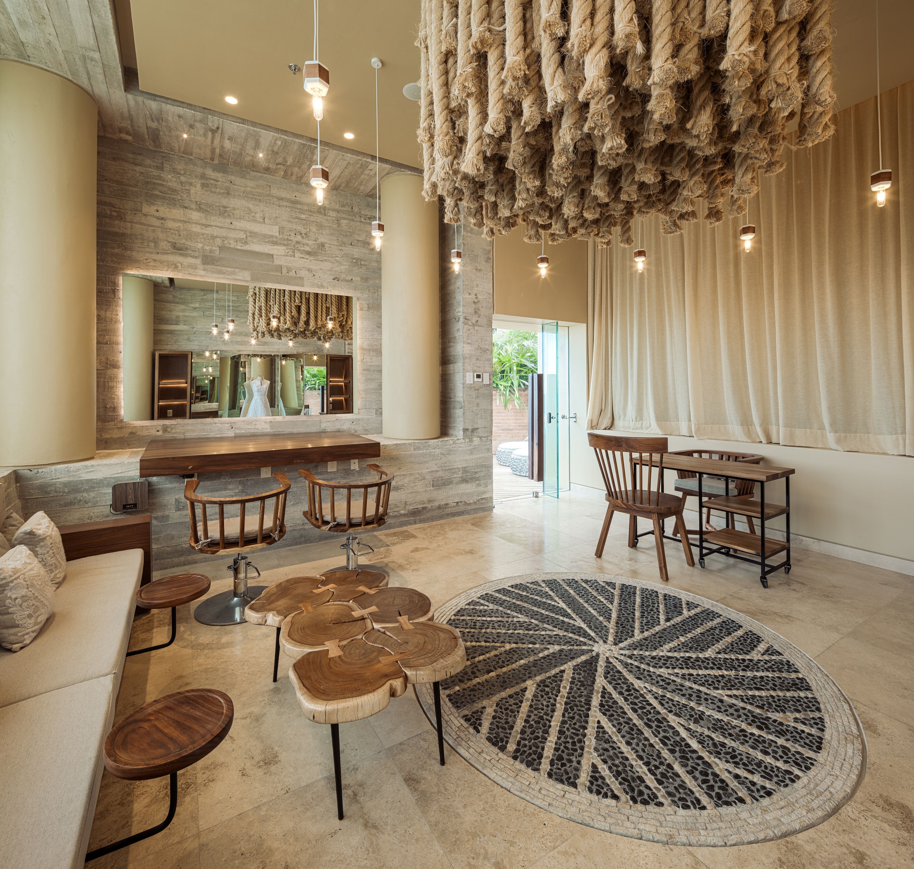 A spacious living area with a large round rug, wooden furniture, and a stone wall.