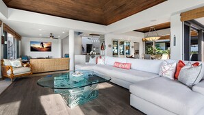 A spacious living area with a glass coffee table, white sofa, and a wooden ceiling. - 🏖️Mauna Lani 4BR Home w/ Private Pool + Central AC (Kamuela)