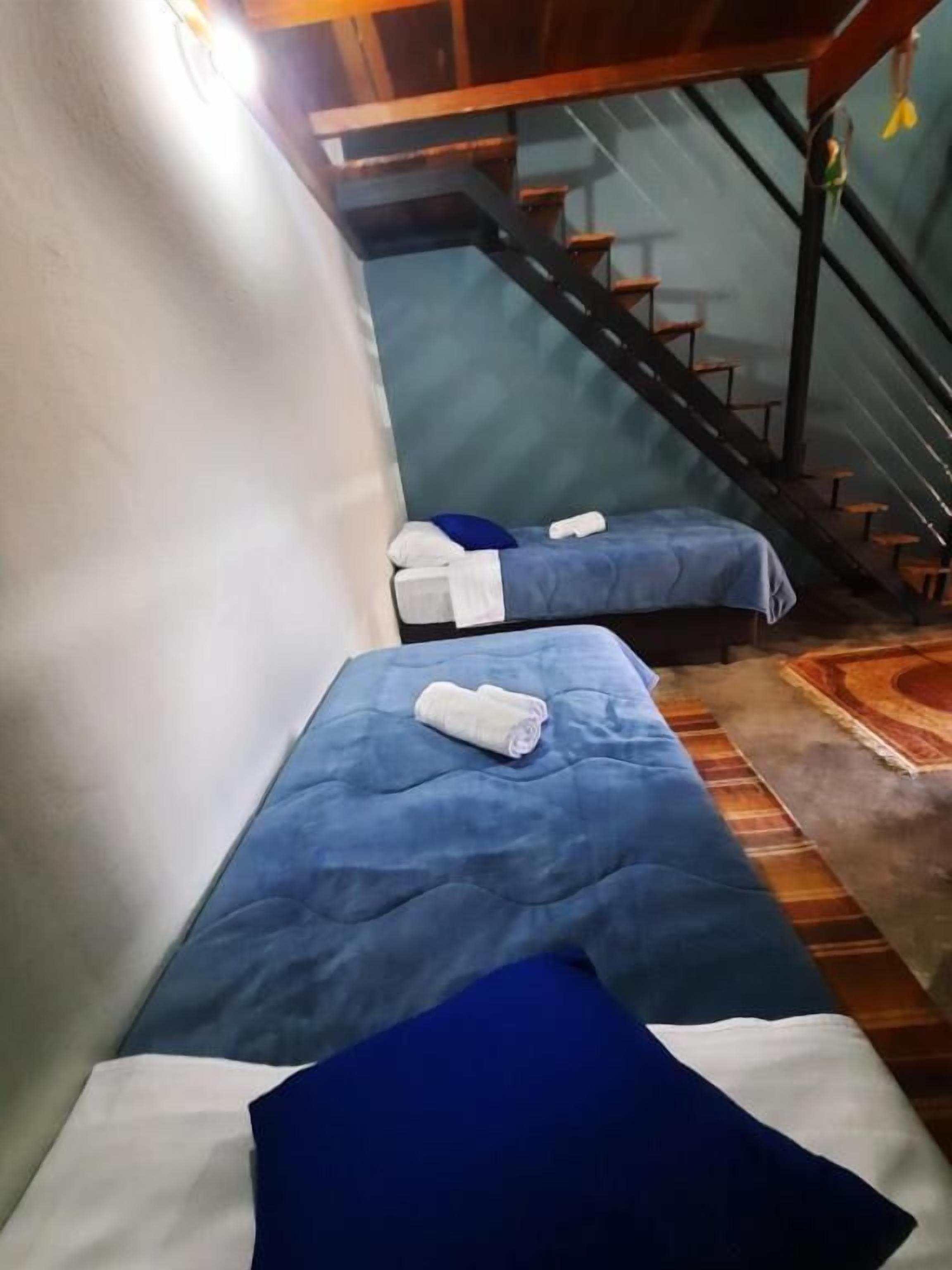 A hotel room with two beds, a staircase, and a view of the outside.