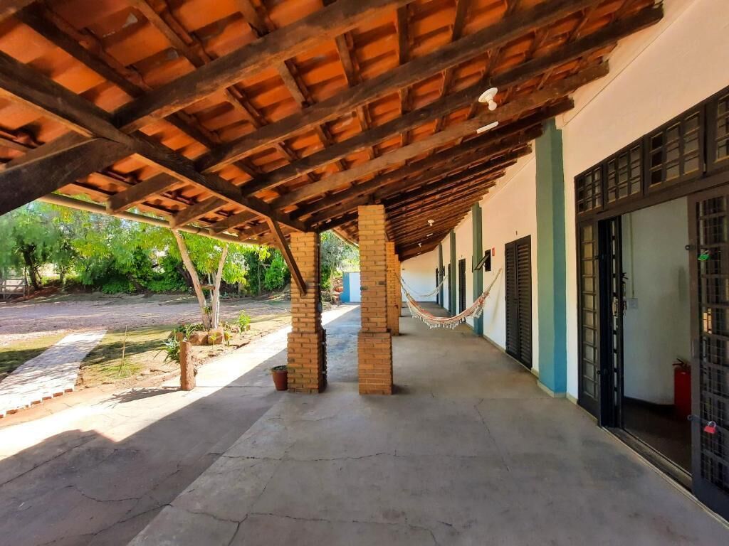 Un espacio al aire libre techado con suelo de hormigón, vigas de madera y pilares de ladrillo.