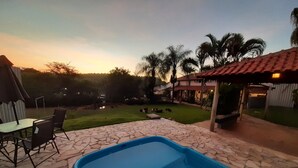 Un patio trasero con piscina, mobiliario de jardín y una zona de estar techada.