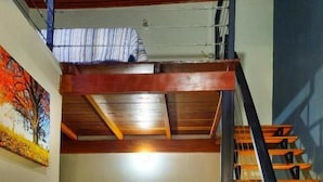 Habitación con literas, una escalera de madera y una cama individual.