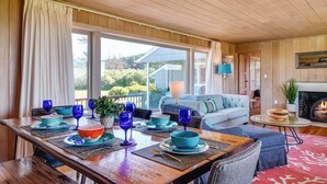 A dining area with a wooden table set for a meal, a sofa, and a fireplace.