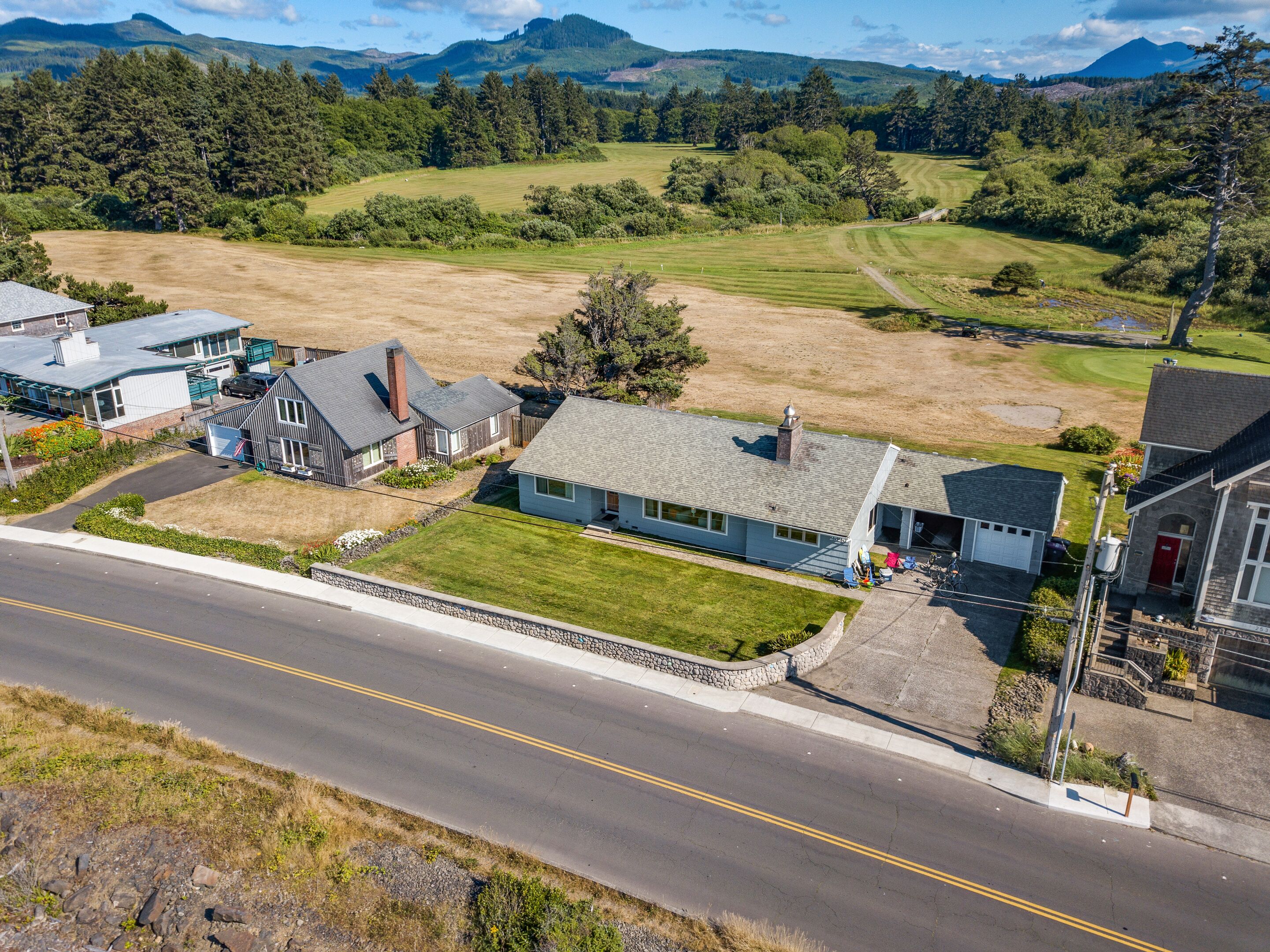 A residential area with houses, a road, and a hilly landscape in the background.