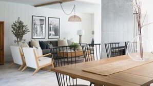 Een eetruimte met een houten tafel en stoelen, een hanglamp en een muur met ingelijste foto's.