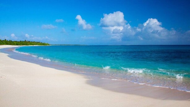 Een strand met helder turquoise water en wit zand.