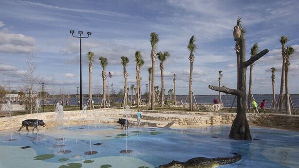 Un parc aquatique doté d’une piscine avec des crocodiles, de palmiers et d’une zone aménagée en plage.