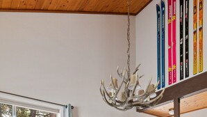 Ruokailutila, jossa on puinen pöytä ja tuolit, kattokruunu sekä seinällä sukset.