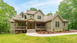 A two-story house with a front porch, a covered entryway, and a landscaped front yard. - Cozy Chalet w/ Lake Access & Game Room (Oakland)