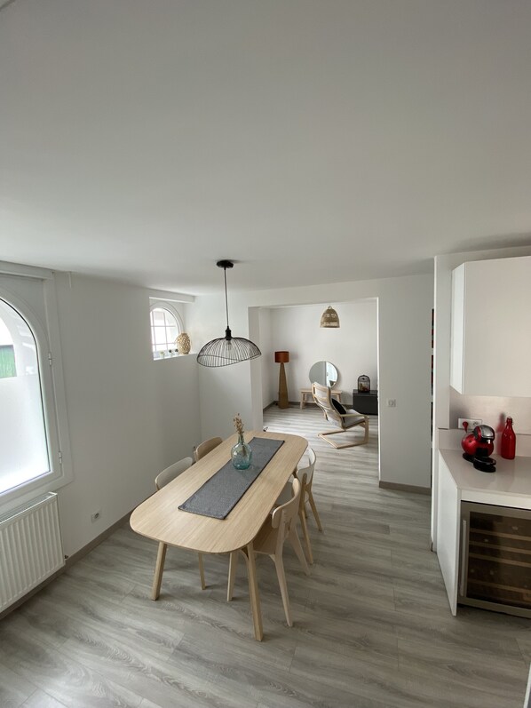 Une cuisine moderne avec une table en bois, des chaises et un luminaire suspendu.