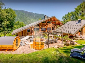 Eine Holzhütte mit einer Veranda, Sitzgelegenheiten im Freien und einem großen Fass.