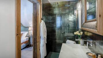 Une salle de bain moderne avec une douche à parois de verre, un lavabo blanc agrémenté d’articles de toilette et un miroir encadré en bois.