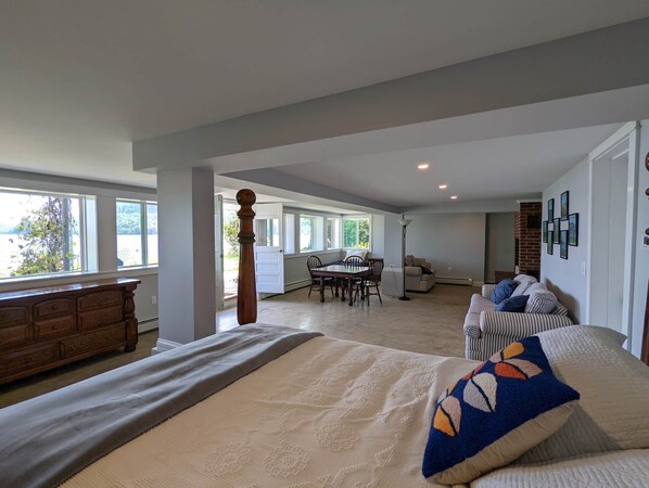 A spacious room with a large bed, a dining area, and a living area with a sofa and a fireplace.