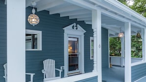 A blue house with a porch, white columns, and a white chair.