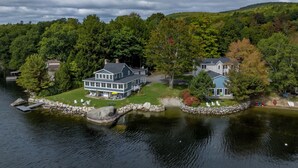 A lakeside property with two main buildings, a dock, and a stone bridge. - Lakefront for 15, private beach and dock (Dedham)