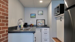 A compact kitchen with a sink, a toaster, and a microwave on the countertop. There are two framed artworks on the wall. - Lakefront for 15, private beach and dock (Dedham)