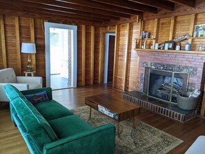 A cozy living room with a green sofa, wooden coffee table, and a fireplace.