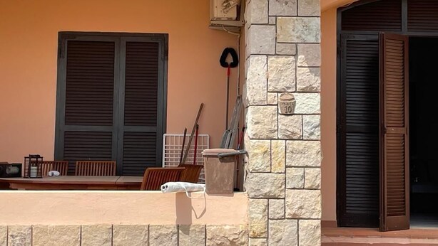Un bâtiment à la façade en pierre, avec un banc en bois et une porte fermée.
