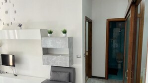 Una sala de estar moderna con un sofá gris, un televisor montado y un reloj de pared.