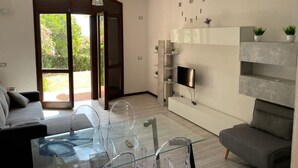 Un salon moderne avec une table basse en verre, un canapé gris et un téléviseur fixé au mur.