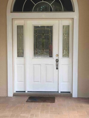 A white front door with a glass panel and a decorative metal grille.