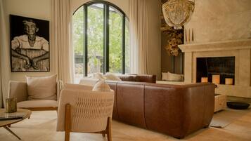 Un salon moderne doté d’une grande fenêtre, d’une cheminée et d’un lustre.