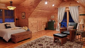 Une chambre confortable dans un chalet en rondins, avec un lit, une commode en bois, une commode verte, une chaise, une petite table et une fenêtre avec des rideaux.