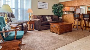 A cozy living room with a sofa, armchair, coffee table, and a dining area with bar stools. - Lake Taneycomo Waterfront Condo | Marina Access + 2 King Beds (AP79-1) (Branson)