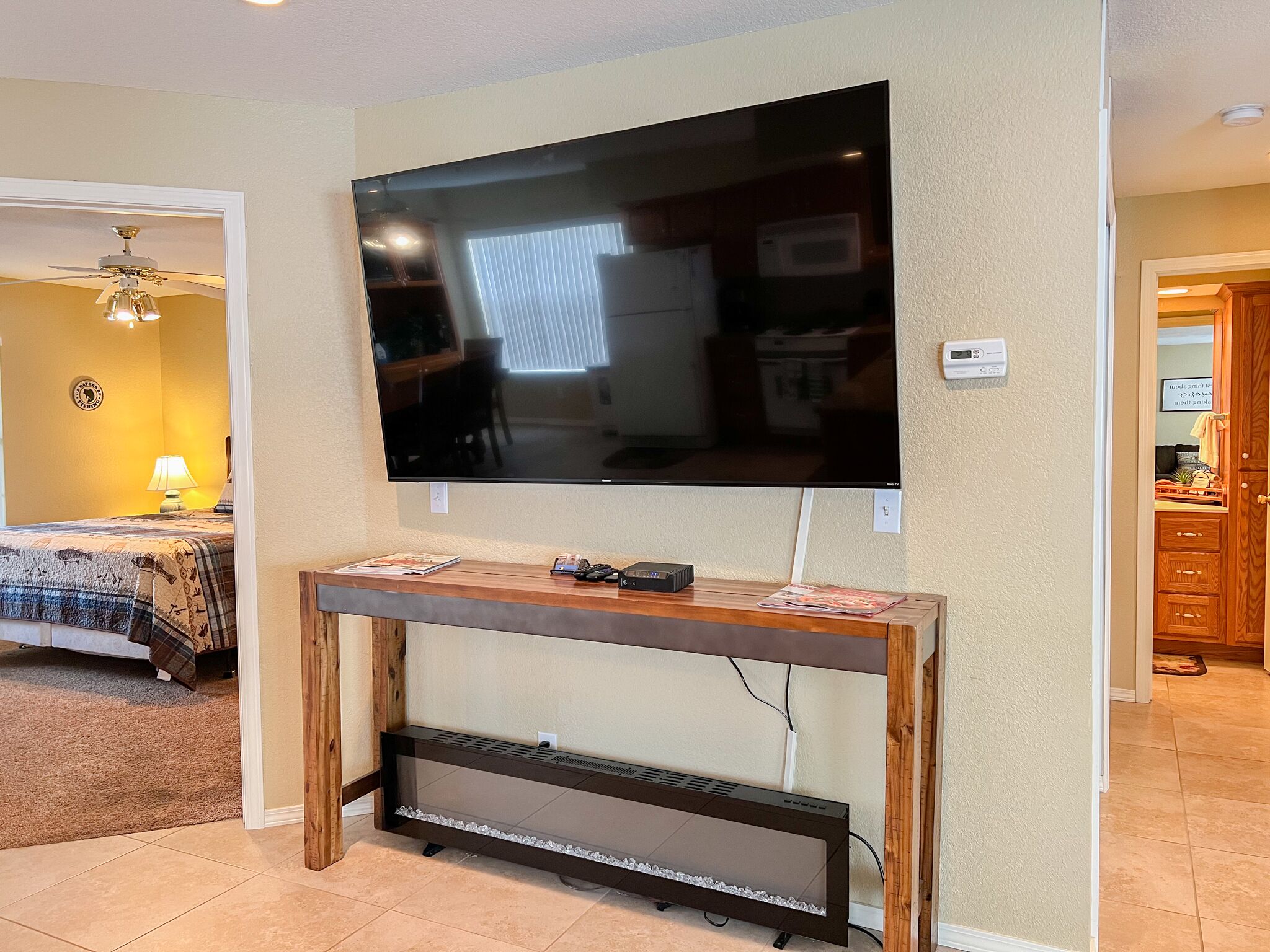 Un televisor de pantalla plana montado en una mesa consola de madera, con un decodificador y un control remoto encima.