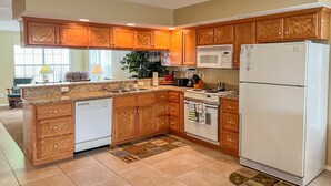 A kitchen with wooden cabinets, a white refrigerator, a microwave, and a stove. - Lake Taneycomo Waterfront Condo | Marina Access + 2 King Beds (AP79-1) (Branson)