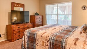 A bedroom with a bed, a dresser, a television, a ceiling fan, and a window with blinds. - Lake Taneycomo Waterfront Condo | Marina Access + 2 King Beds (AP79-1) (Branson)