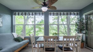 Ein Zimmer mit einer Couch, einem Esstisch, Stühlen und einem Deckenventilator.