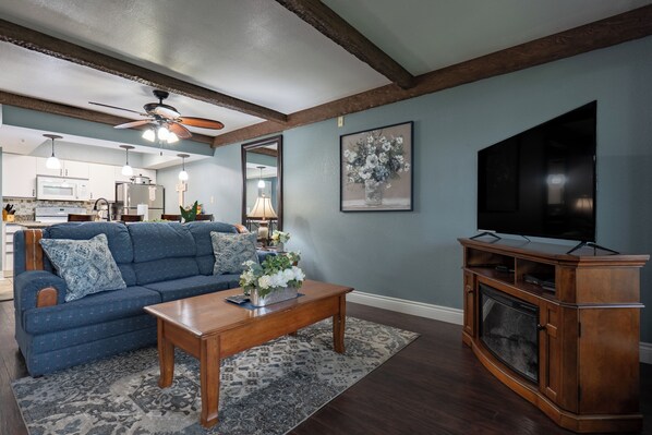 A living room with a blue sofa, wooden coffee table, and a fireplace. - Family-Friendly Branson Condo w/ 2 Queen Beds + Pool | Club A-6 (Branson)