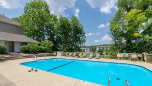 A swimming pool with lounge chairs and a building in the background.