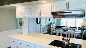 Una cocina moderna con armarios blancos, una campana extractora de acero inoxidable y una placa de inducción integrada.