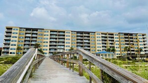 Un muelle de madera que conduce a un edificio residencial de varios pisos con balcones.