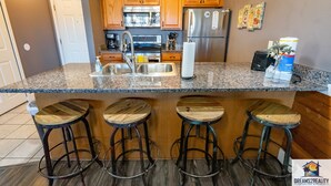 Una cocina moderna con gabinetes de madera, electrodomésticos de acero inoxidable y una encimera de granito.
