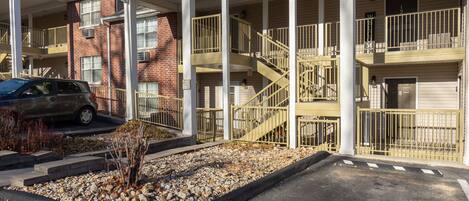 A multi-story building with a covered outdoor area, a staircase, and a parking lot.