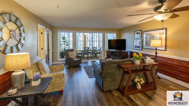 A spacious living room with a large clock, a ceiling fan, and a television. - Walk-In Branson Condo w/ Pool + Easy Access | Club C-7 (Branson)