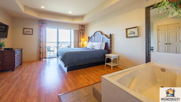 Un dormitorio con una cama grande, un baño con bañera y un balcón con vistas.